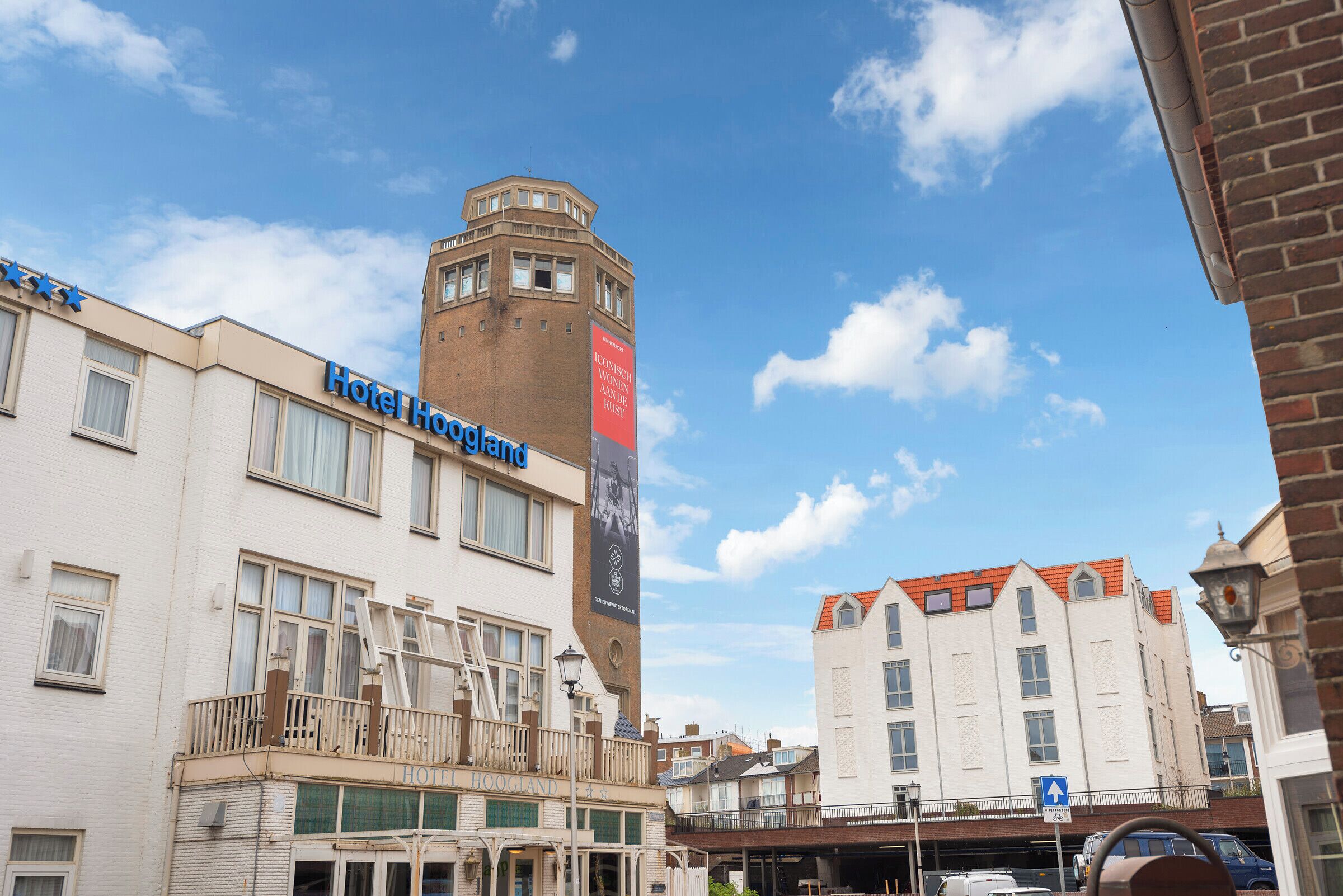 Hotel Hoogland con una imponente torre en esquina y un cartel que anuncia un museo.