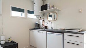 Une petite cuisine équipée comprenant une cuisinière intégrée, un évier et un égouttoir à vaisselle.