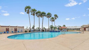 A swimming pool with palm trees, lounge chairs, and a lifeguard stand.