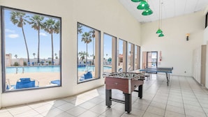 A room with large windows, a foosball table, and a pool view.