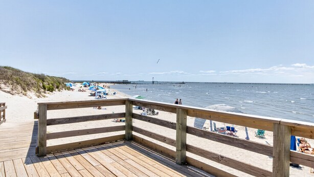 A wooden deck leading to a beach with umbrellas and lounge chairs. - Nautical Miles Home, Close to Park, Beach & Shops (Cape Charles)