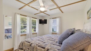 A bedroom with a bed, a ceiling fan, a TV, and windows with curtains. - Nautical Miles Home, Close to Park, Beach & Shops (Cape Charles)