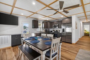 A modern kitchen with dark cabinets, stainless steel appliances, and a dining area with a wooden table and chairs.