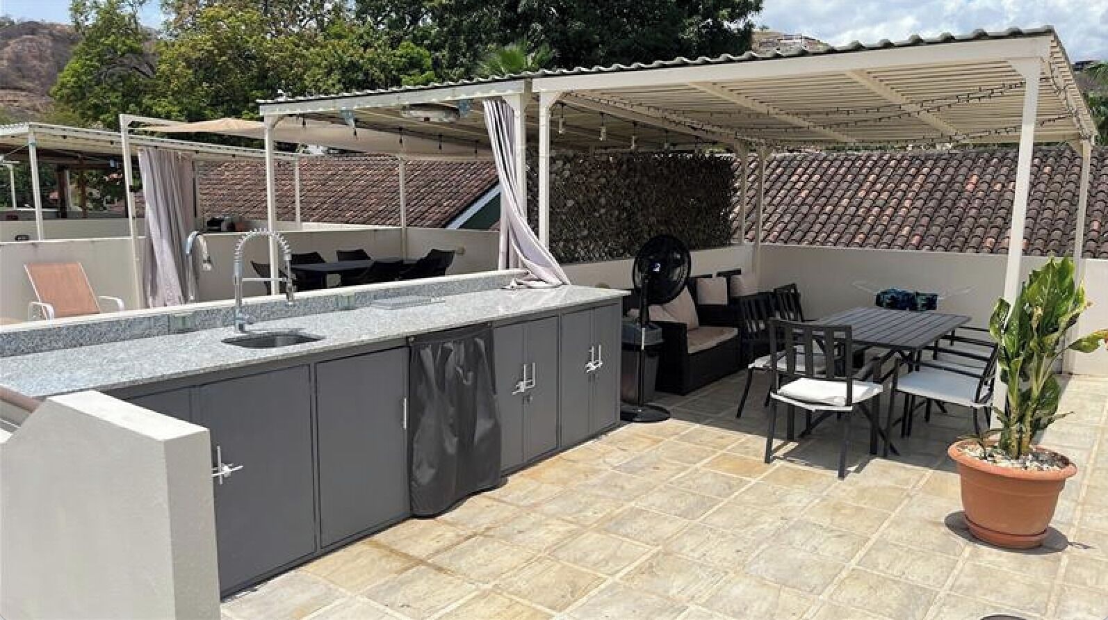 An outdoor kitchen area with a built-in grill, dining table, and chairs.