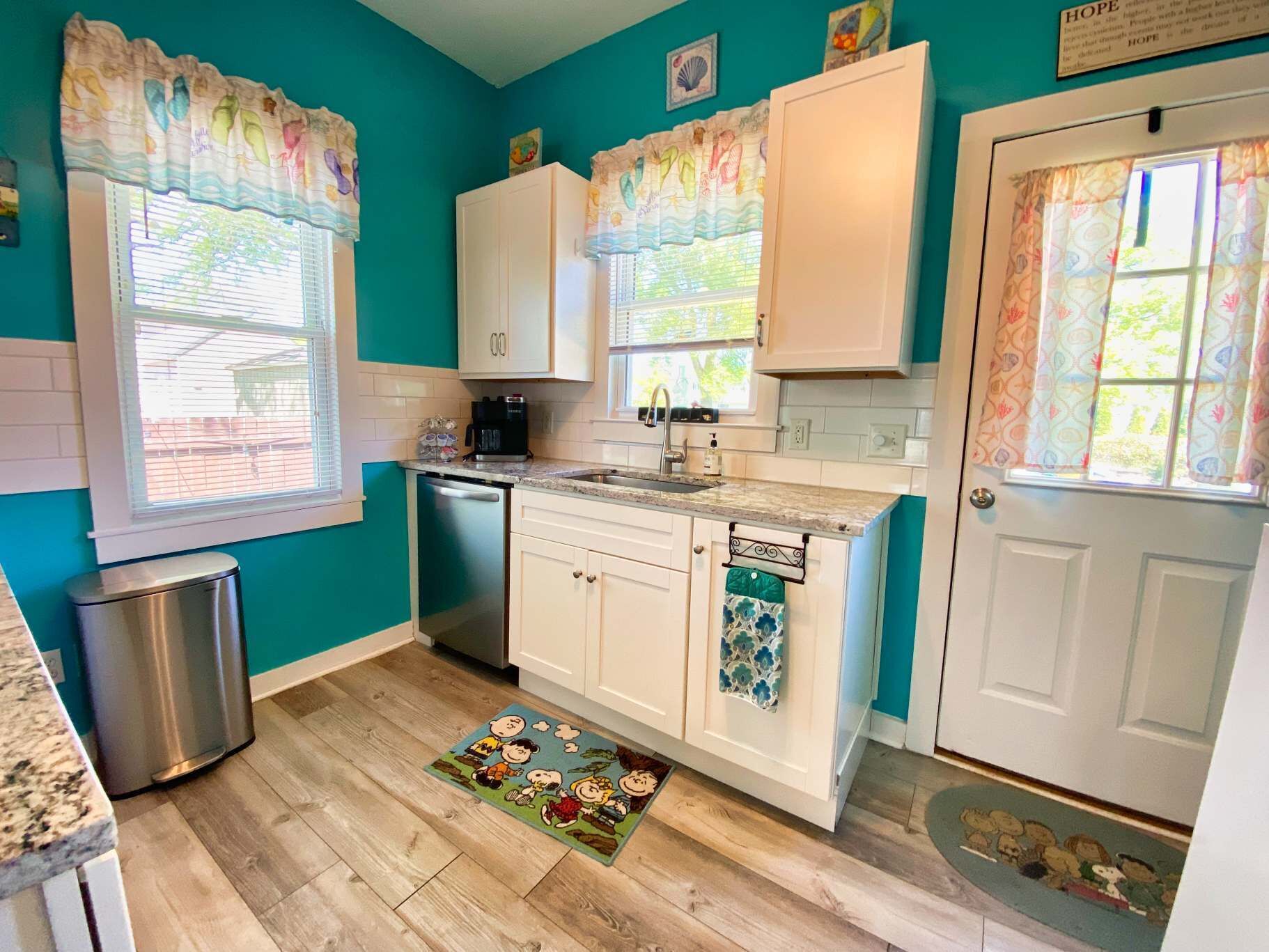 A kitchen with teal walls, white cabinets, a stainless steel dishwasher, and a coffee maker.