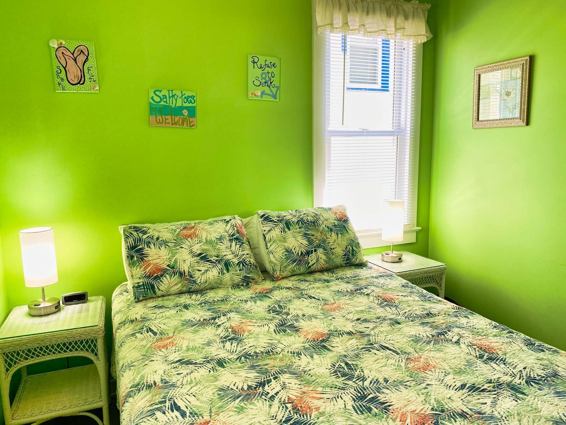 A room with a bed, a nightstand, a lamp, and a window with blinds.