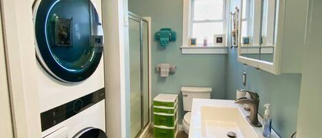 A compact bathroom with a built-in washer and dryer, a toilet, and a sink.