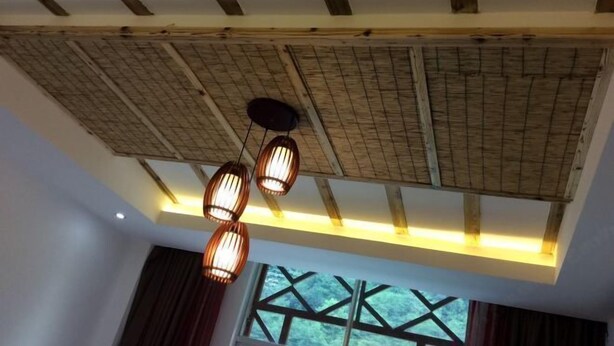 Una habitación con techo alto, vigas de madera a la vista y un amplio ventanal con diseño geométrico.