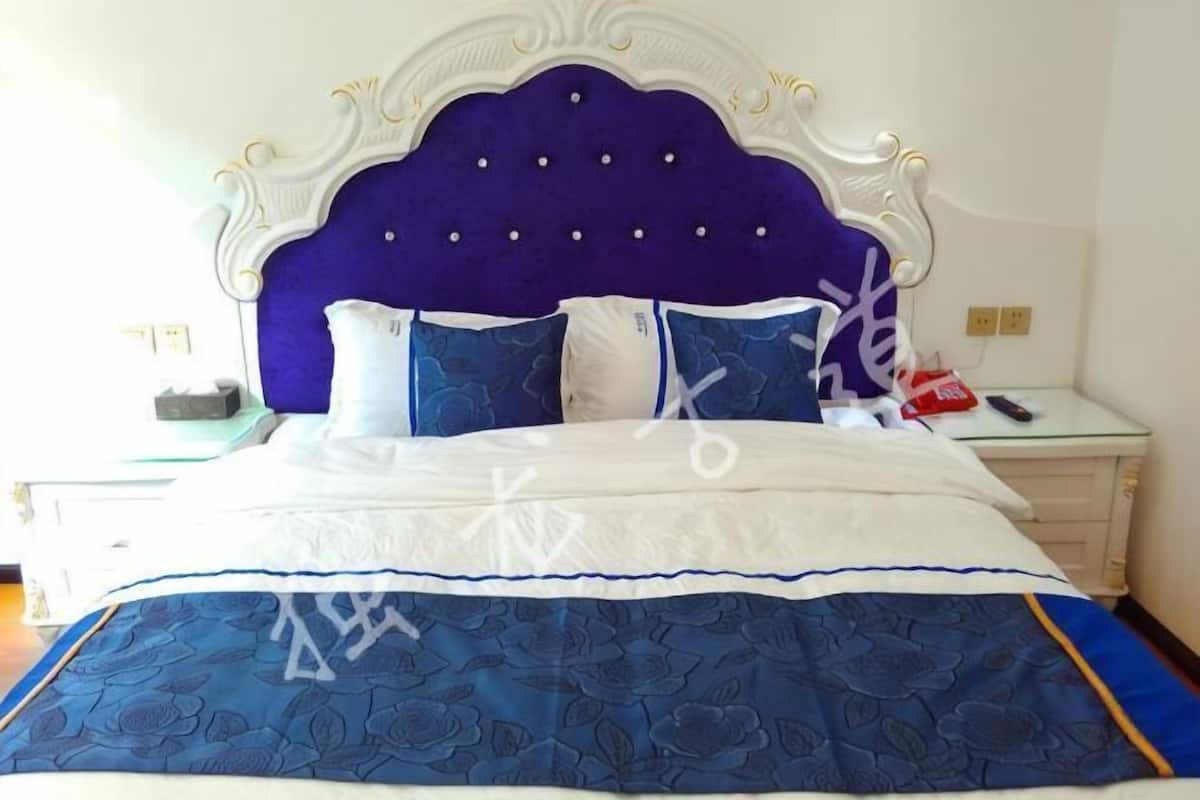 A bed with a white and blue bedspread, a purple headboard, and two bedside tables with lamps.