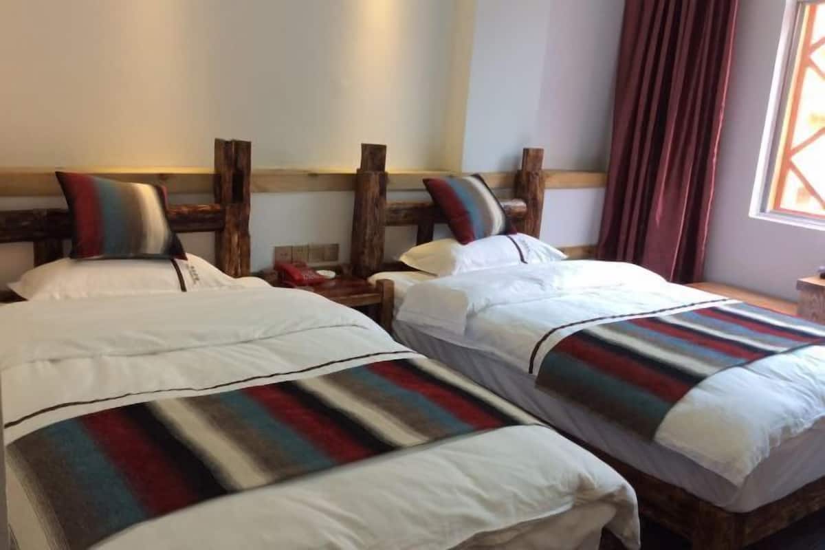A double bed with a striped blanket, a wooden headboard, and a nightstand with a lamp.