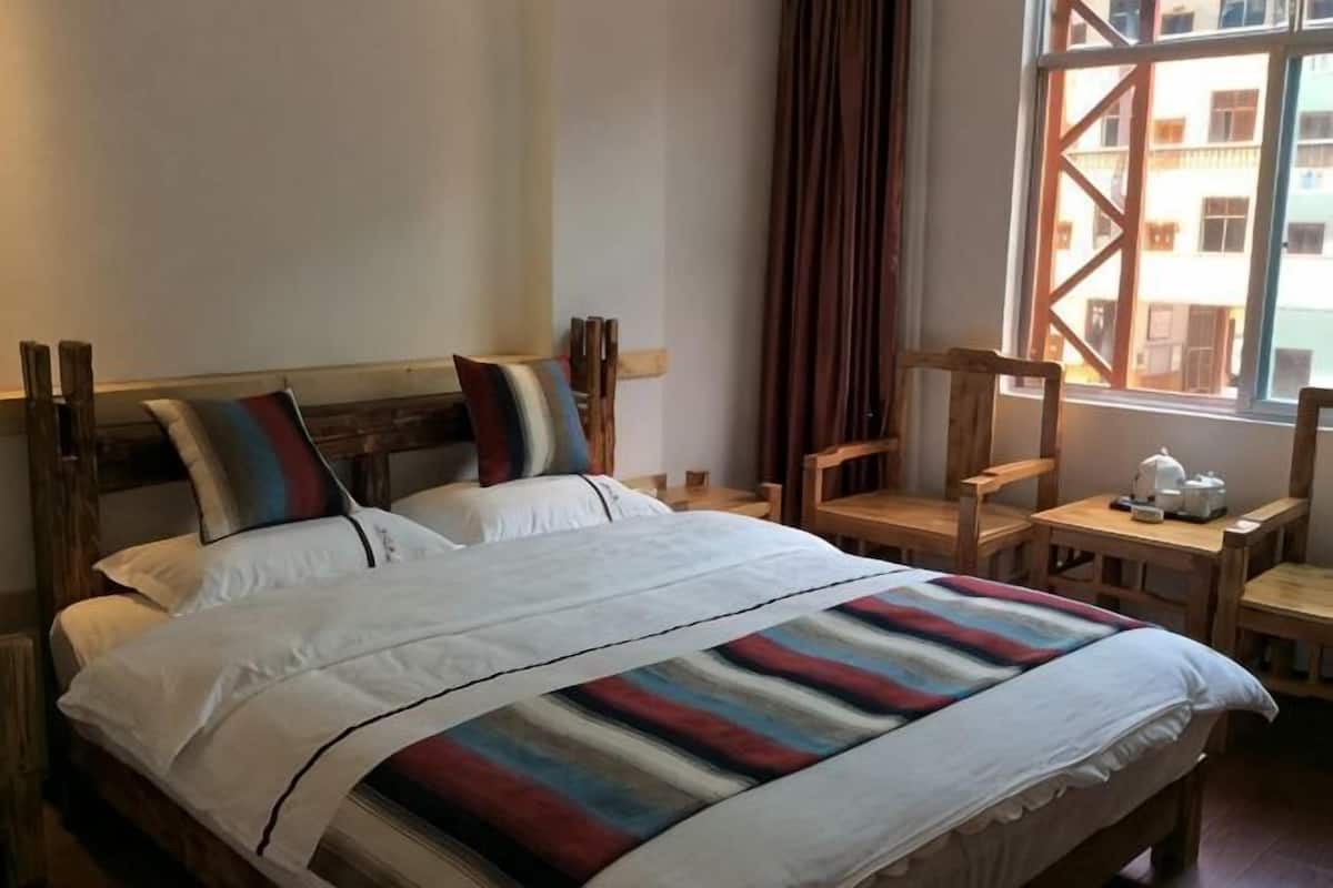 A bed with a striped blanket, a wooden headboard, and two pillows.