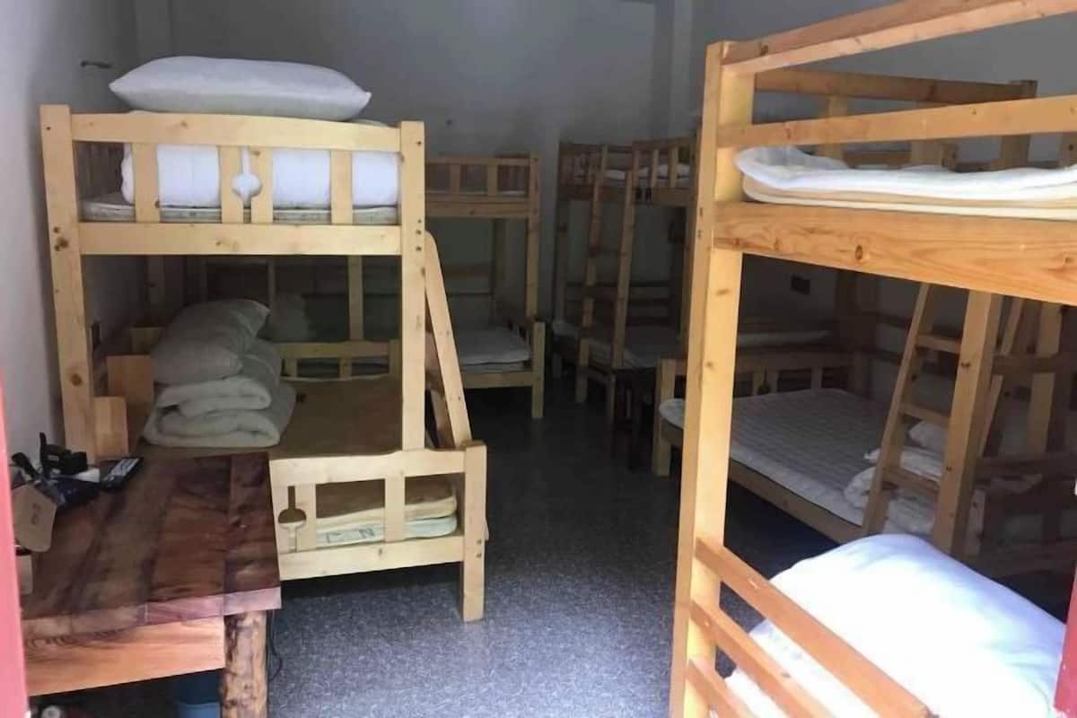 A room with bunk beds, a small wooden table, and a chair.