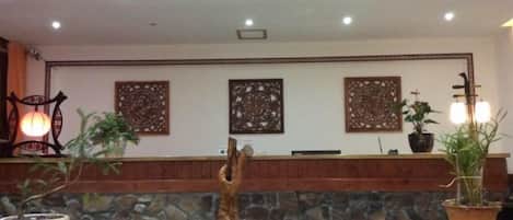 A reception area with a stone wall, wooden counter, and potted plants.