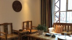 Una habitación acogedora con muebles de madera, una mesa redonda y una ventana con cortinas.