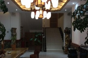 Un hall d’entrée avec un escalier, un lustre et des plantes en pot.