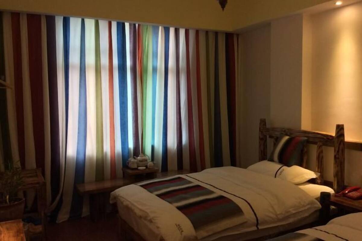A hotel room with a bed, bedside table, and curtains.