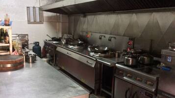 A commercial kitchen with stainless steel appliances, including a stove, pots, and a refrigerator.