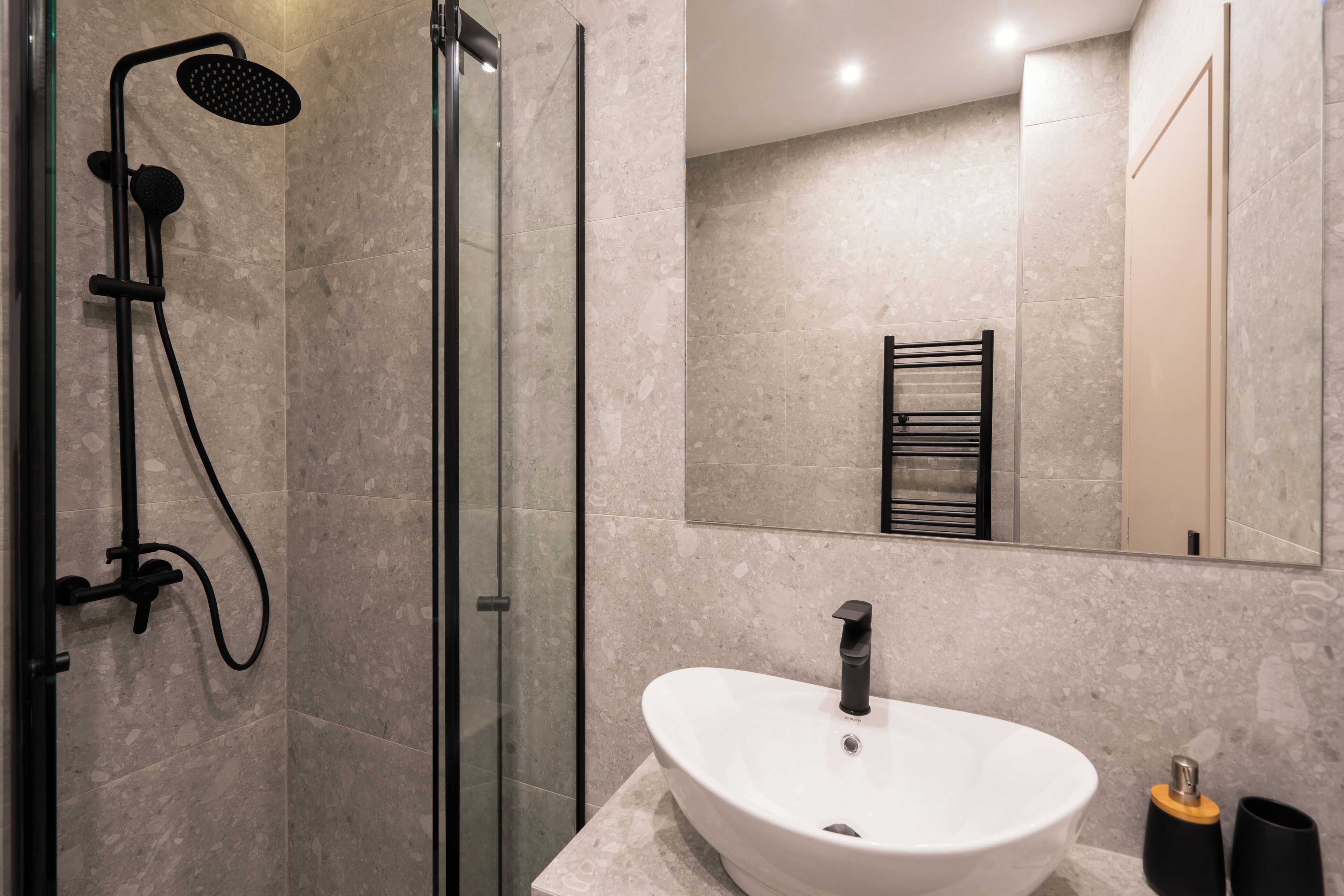 A modern bathroom with a glass-enclosed shower, a white sink, and a large mirror.