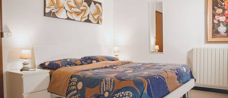 A bedroom with a bed, nightstands, a mirror, and artwork on the walls.