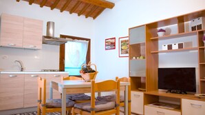 A compact kitchen with wooden cabinets, a built-in stove, and a dining area with a table and chairs. - 1 Bed-sleeps 4-town Centre-free Parking-aircon (Montagnana)