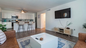 A modern living room with a flat-screen TV, a coffee table, and two sofas.
