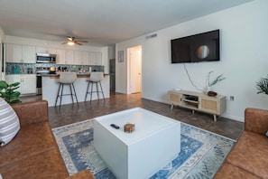 A modern living room with a flat-screen TV, a coffee table, and two sofas. - Fillmore Unit #7 | 2BR/1BA (Cape Canaveral)