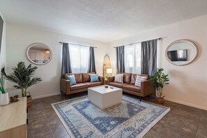 A living room with two sofas, a coffee table, and a patterned rug.