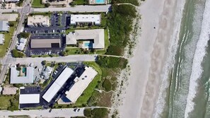 Ett flygbildsbild av ett kustområde med byggnader, en strand och vågor som bryter mot havet.