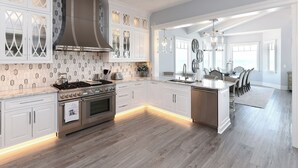 Une cuisine moderne avec des meubles blancs, un grand îlot central et une cuisinière intégrée.