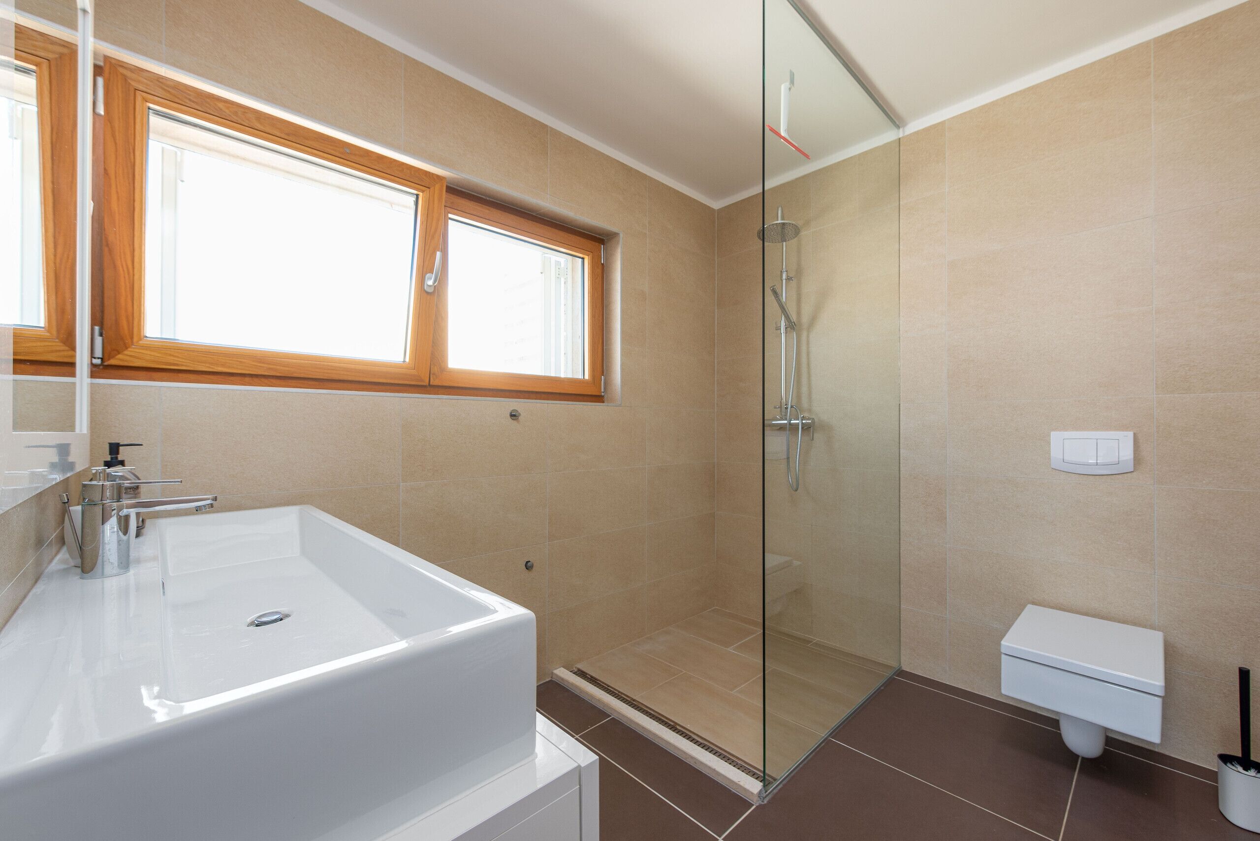 Un baño moderno con una bañera blanca grande, cabina de ducha con mampara de vidrio y un inodoro.