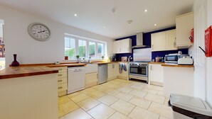 A modern kitchen with white cabinets, a stainless steel stove, and a microwave. - 5-bedroom Home - Sleeps 16 - Ideal for Groups (Doncaster)