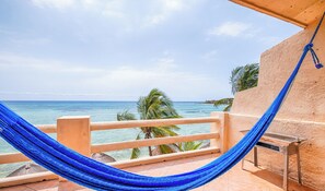 Un hamac sur un balcon donnant sur une plage bordée de palmiers et sur l’océan.