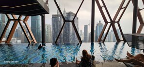 An infinity pool with a cityscape view, surrounded by a modern architectural structure. - The Scarletz KLCC (Kuala Lumpur)