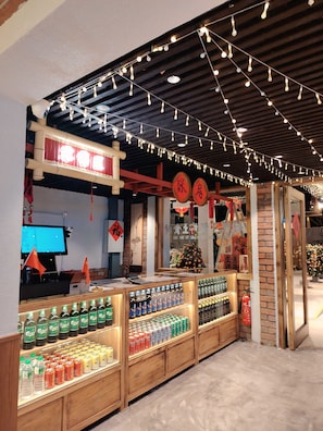 A retail area with shelves stocked with beverages, a cash register, and decorative lights. - The Scarletz KLCC (Kuala Lumpur)