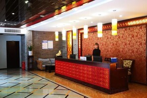 A hotel reception area with a reception desk, a receptionist, and a patterned wall. - Yunxi Yard Hotel (Youyang County)