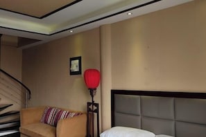 A hotel room with a sofa, a bed with a headboard, a staircase, and a red floor lamp. - Yunxi Yard Hotel (Youyang County)