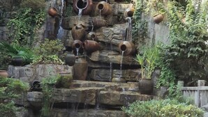 Una pared de roca con múltiples jarrones y una cascada pequeña.