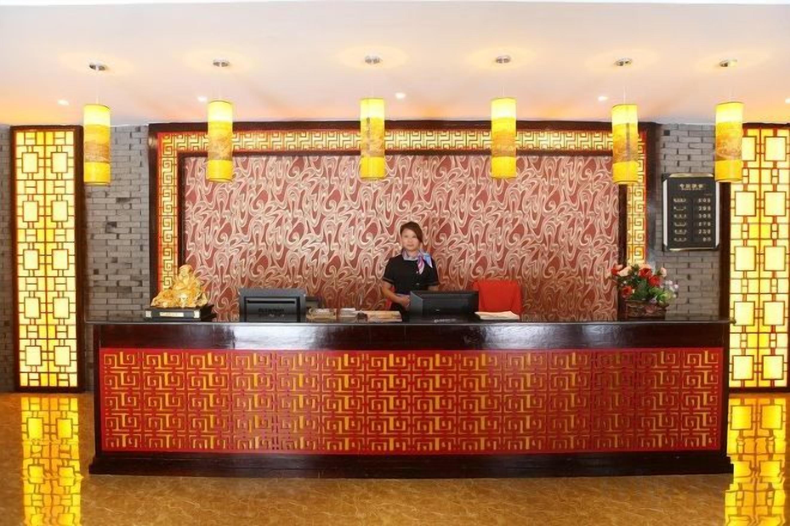 Un comptoir d'accueil avec un panneau décoratif à motifs et une réceptionniste.