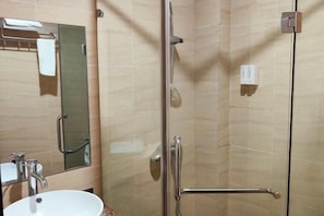 A bathroom with a glass shower enclosure, a sink, a mirror, and a towel rack.