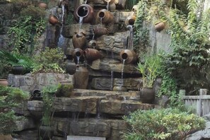 Un jardín rocoso con fuentes escalonadas y diversos maceteros.
