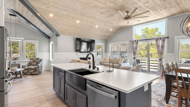 A modern kitchen with a large island, built-in appliances, and a ceiling fan.