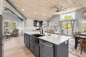 A modern kitchen with a large island, built-in appliances, and a ceiling fan.