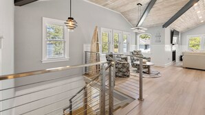 A spacious living area with a high ceiling, a staircase, and a view of the outdoors.