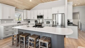 A modern kitchen with white cabinets, stainless steel appliances, and a large island with stools.