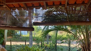 A hammock under a wooden pergola with a view of a well-maintained garden and a pathway. - Pousada Cais Dourado (Maraú)