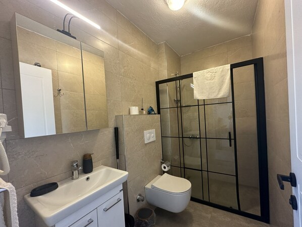 A bathroom with a white sink, mirror, toilet, and glass-enclosed shower. - Villa Carian Trail evdatca, Kargı Bay Datca, close to the beach (Datça)