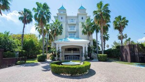 A grand hotel with a central courtyard, palm trees, and a fountain.