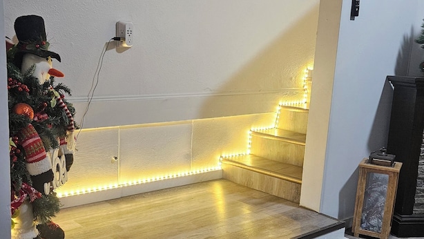 Portaat, joissa on LED-valot, seinälle kiinnitetty kello ja koristeellinen joulukuusi.