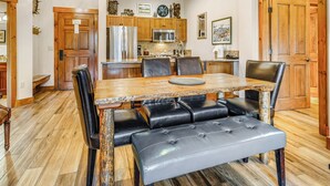 A dining area with a wooden table, black leather chairs, and a bench. - Mountain Thunder Bluebird Condo: Ski In, Top-Floor w/ Views, Resort Amenities (Breckenridge)
