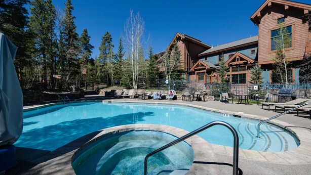 A pool area with a hot tub, lounge chairs, and a wooden lodge in the background. - Mountain Thunder Bluebird Condo: Ski In, Top-Floor w/ Views, Resort Amenities (Breckenridge)